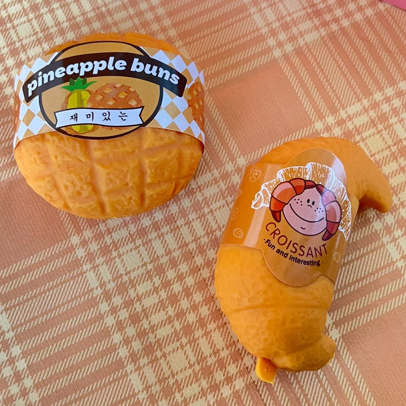 "Hand squeezing realistic croissant squeeze toy showing soft and chewy texture"
