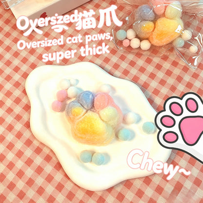 "Individually packaged plush cat paw squishy toy with colorful pom-pom details"