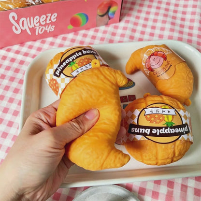 "Hand squeezing realistic croissant squeeze toy showing soft and chewy texture"