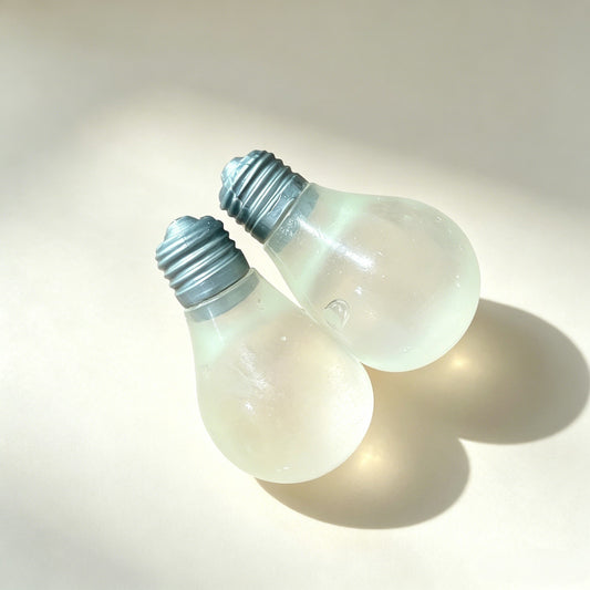 "Hand holding two light bulb-shaped squishy toys daytime and glowing effect"